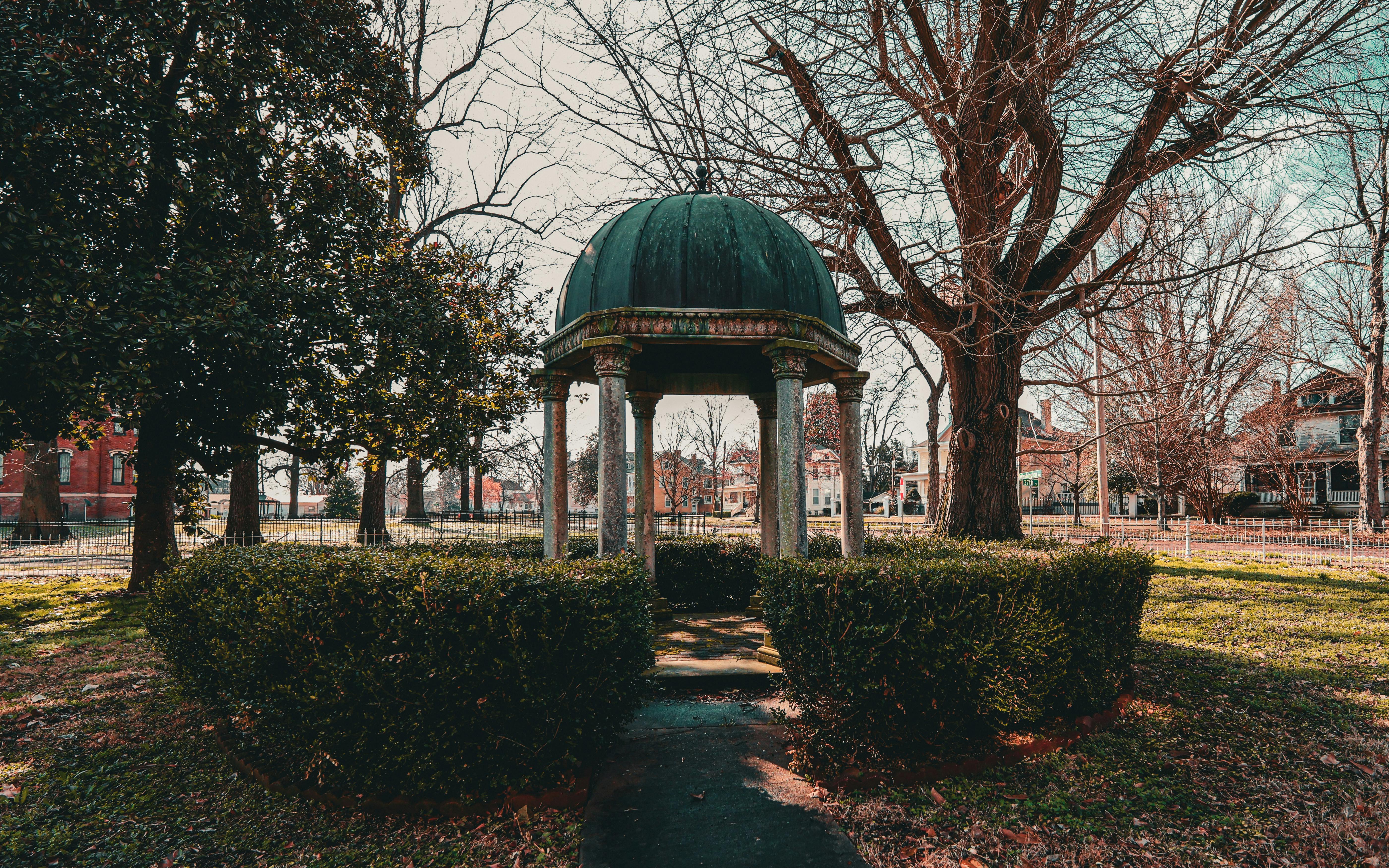 無料 静かな公園にある、木々や茂みに囲まれた素朴なガゼボ。リラックスするのに最適です。 写真素材