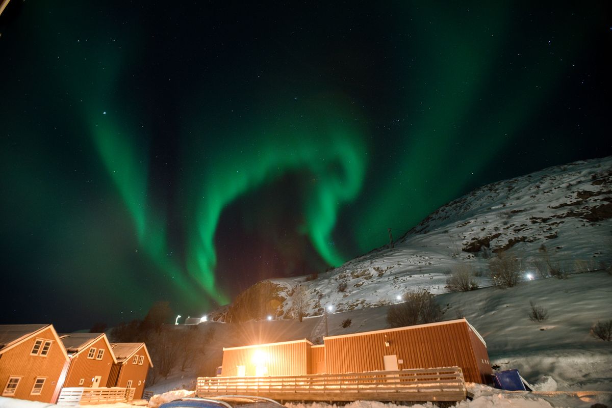 Aurora boreala verde deasupra unui sat innevat