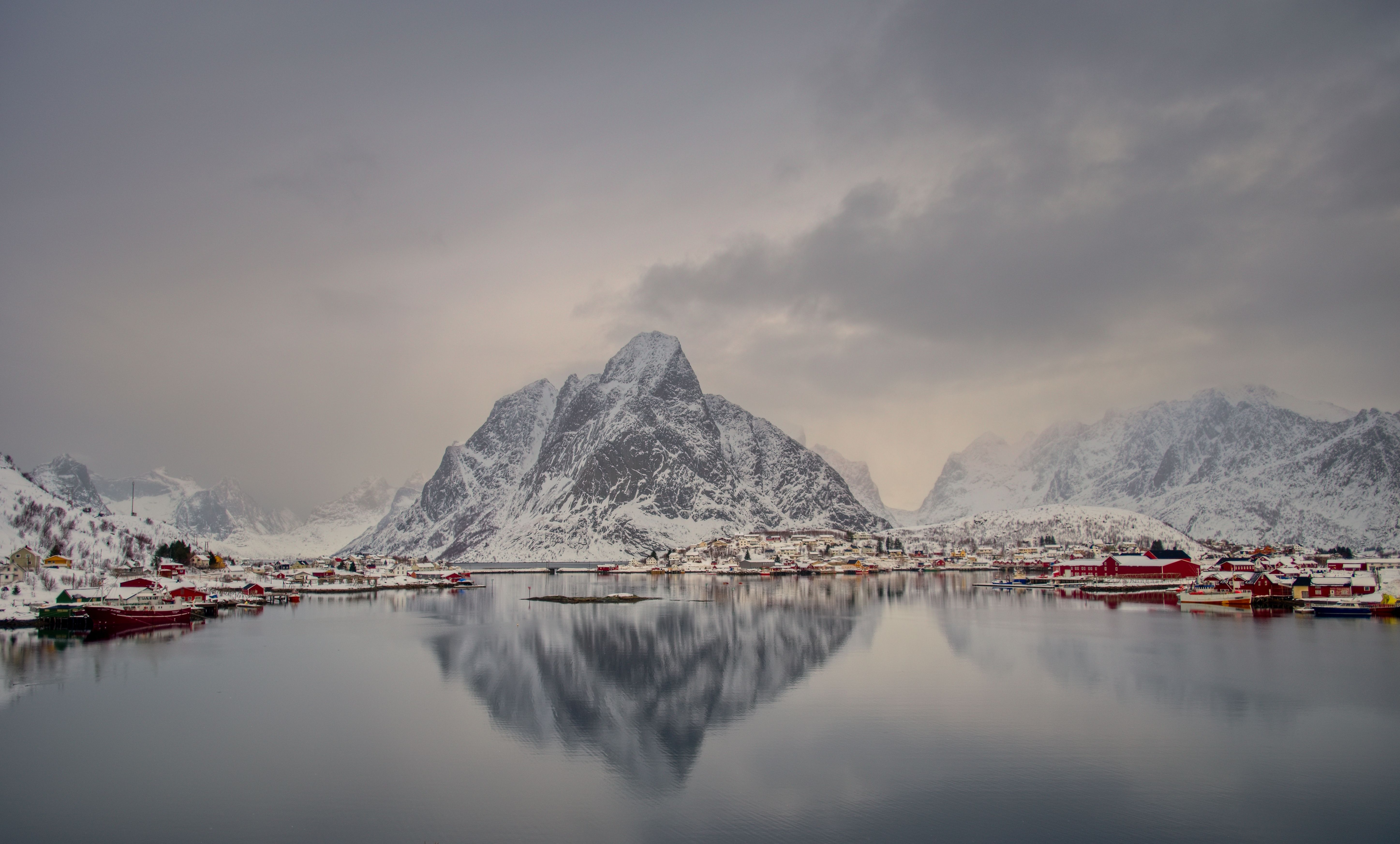 A picturesque winter scene of Reine village in Lofoten, reflecting in still waters.