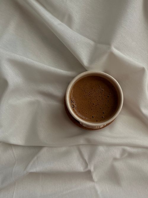 Free Minimalist image of a coffee cup on white fabric, captured from above, highlighting simplicity. Stock Photo