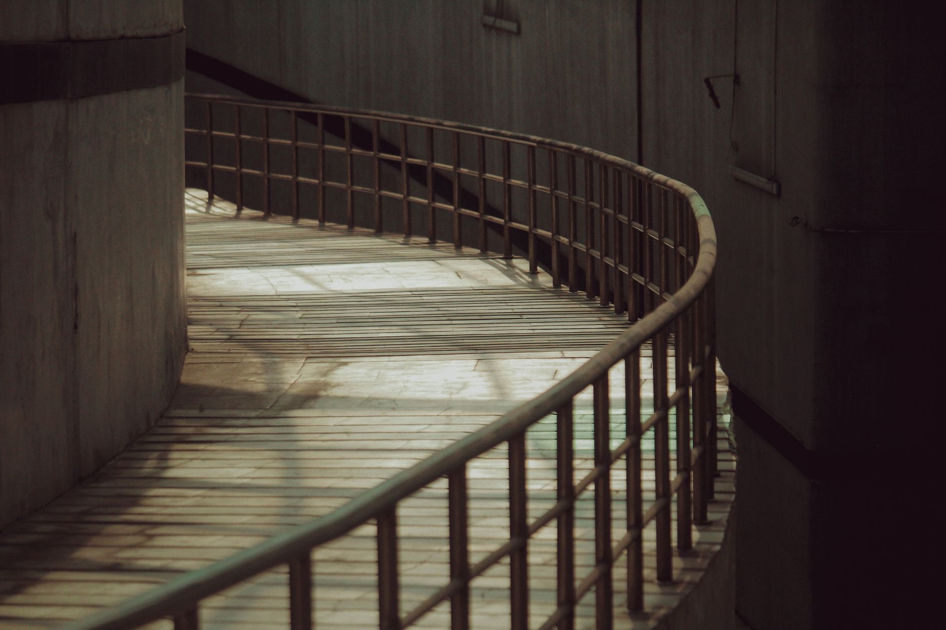 Metal Bending Radius: How to Calculate and Avoid Cracks插图2 A curved wooden pathway with railings in an industrial urban environment, casting shadows.