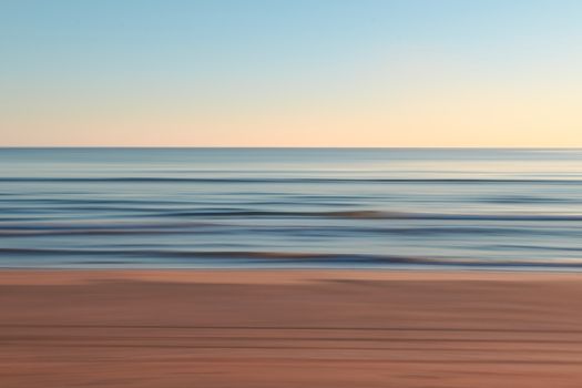 Blurry long exposure of a tranquil ocean at dusk, creating a serene and calming atmosphere.