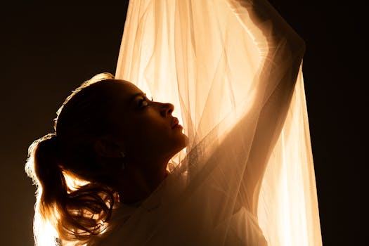 A graceful female in silhouette with highlighted hair and fabric, evoking elegance and mystery.