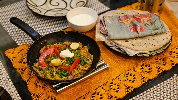A vibrant Indian meal featuring a spicy dish, roti, and yogurt chutney on a tastefully set table.