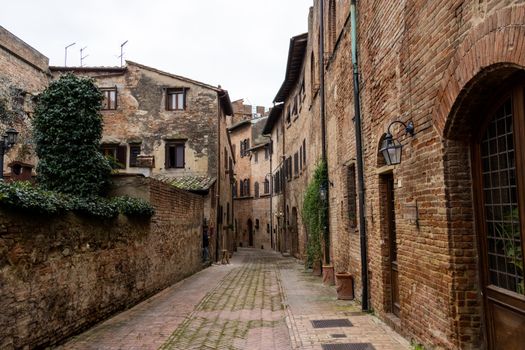 A picturesque ancient street in Certaldo, Tuscany, showcasing rustic stone buildings and a quaint alleyway.