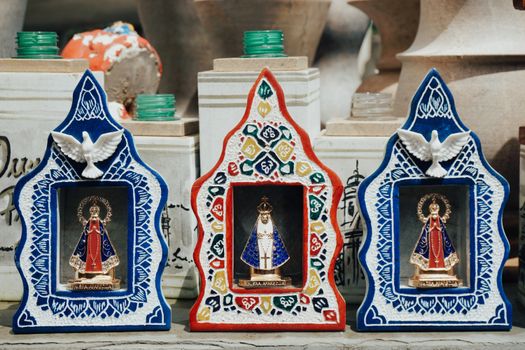 Decorative religious figurines with doves and intricate patterns displayed in vibrant frames.