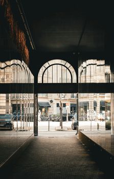 A moody urban scene in Paris featuring a 19th-century archway with building reflections.