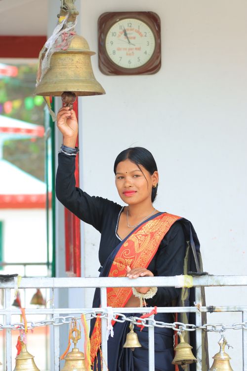 Woman Ringing Bell in Traditional Attire Outdoors · Free Stock Photo