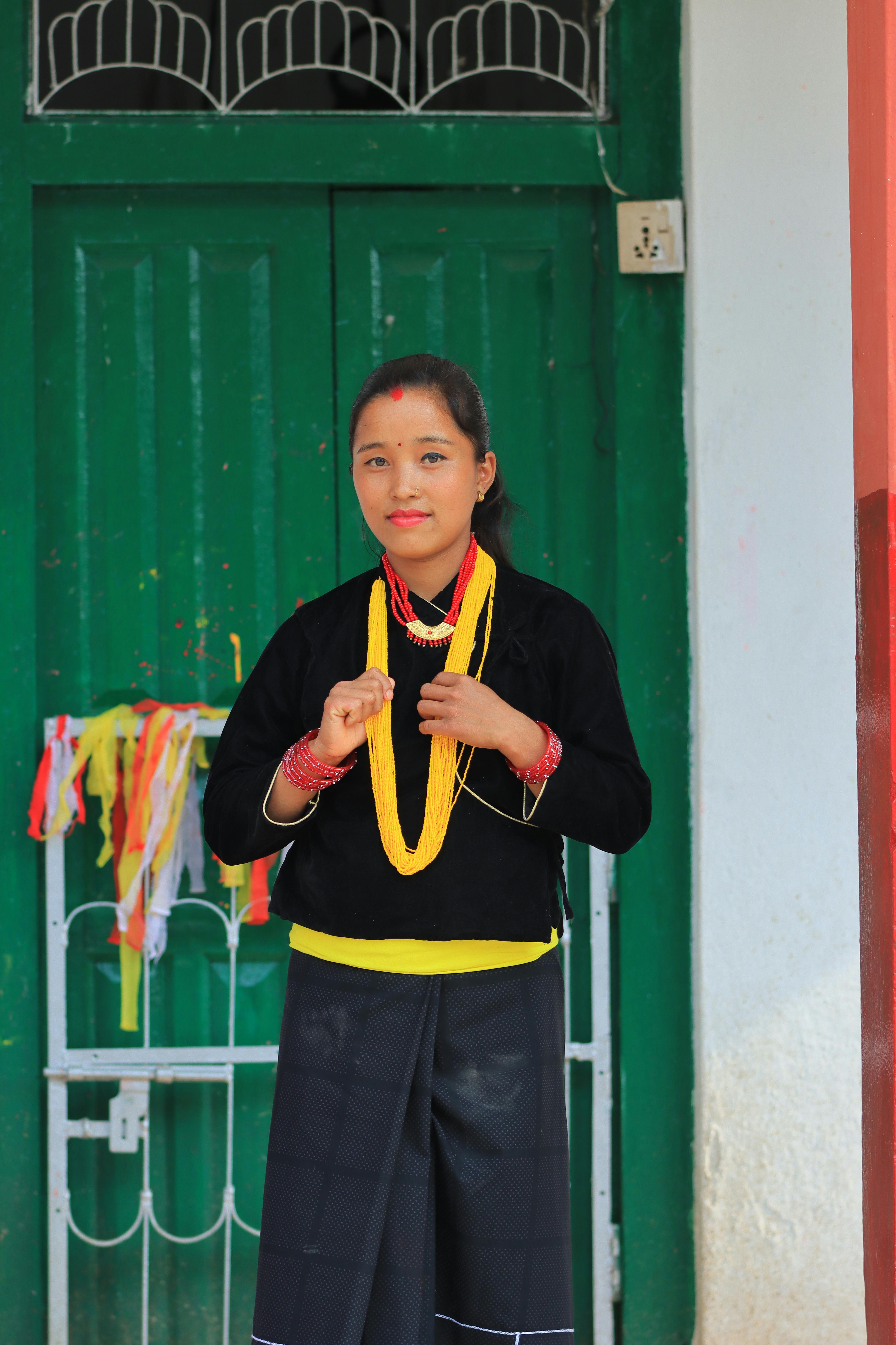 A young woman in traditional Nepali attire standing against a green door.