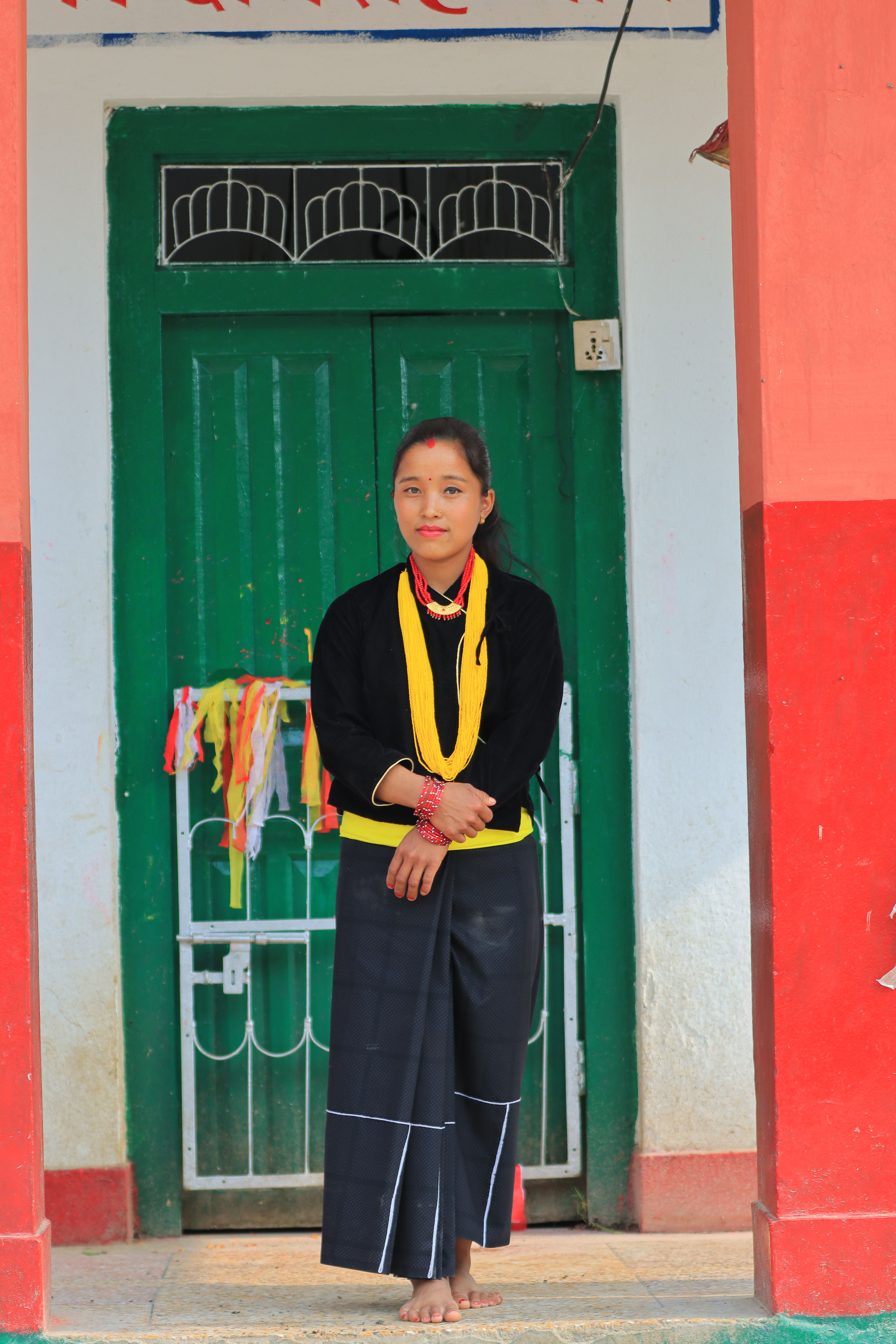 Fotomural Una mujer vestida con ropa tradicional se encuentra en una entrada colorida, mostrando el patrimonio cultural.