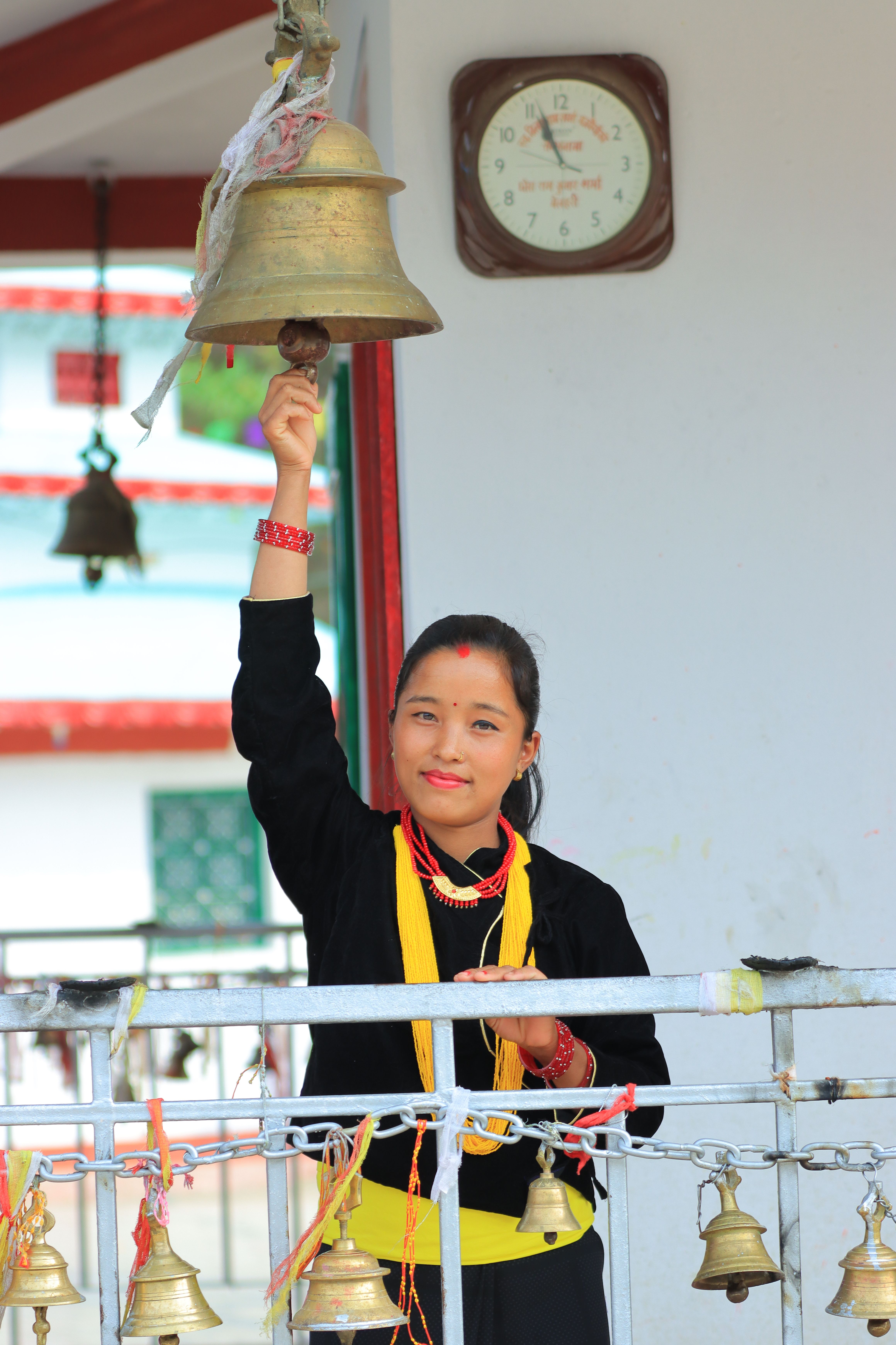 Woman Ringing Temple Bell in Traditional Attire · Free Stock Photo