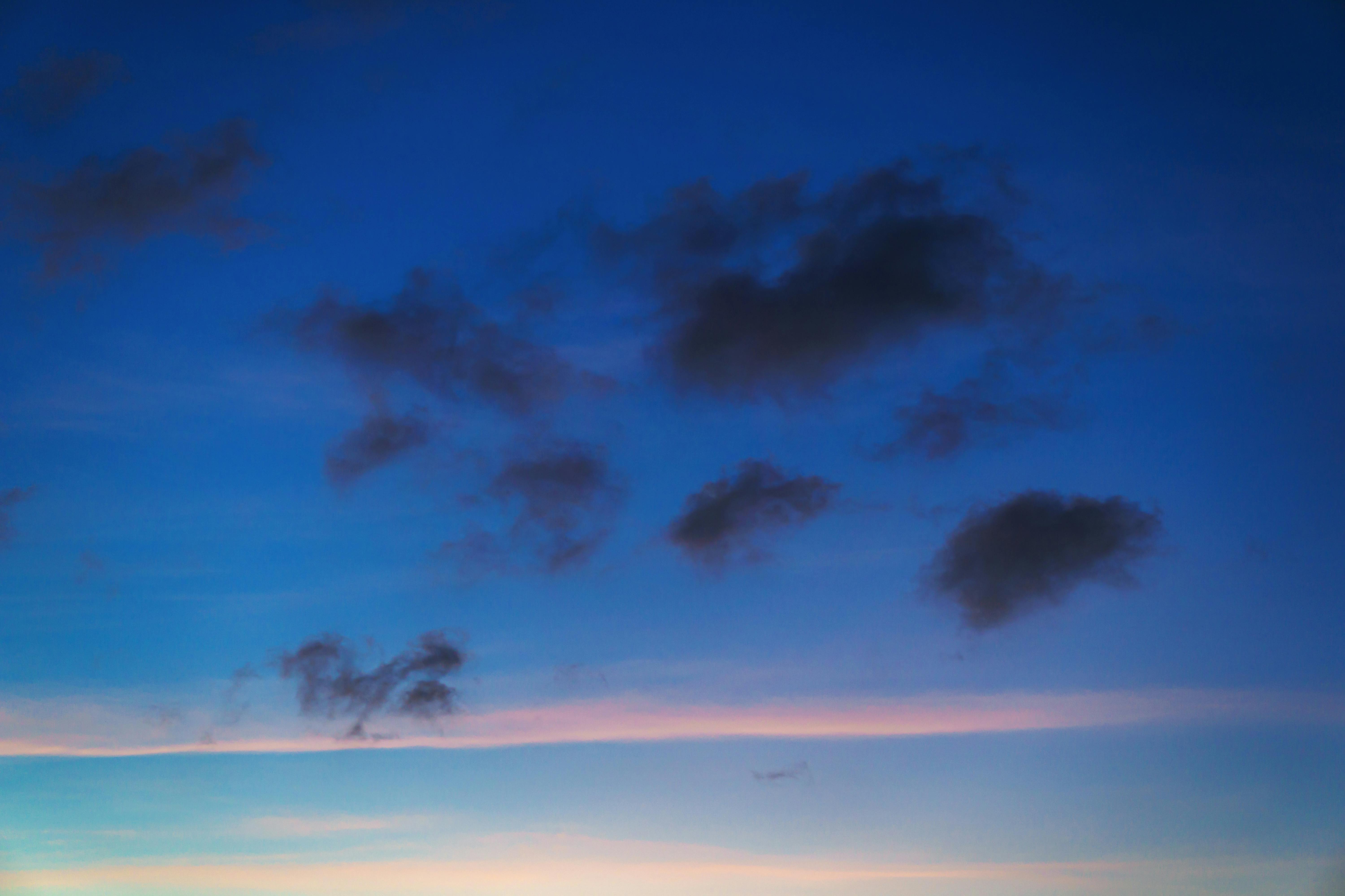 無料 暗い雲と青とピンクの色合いのグラデーションがある、静かで穏やかな夕暮れの空。 写真素材