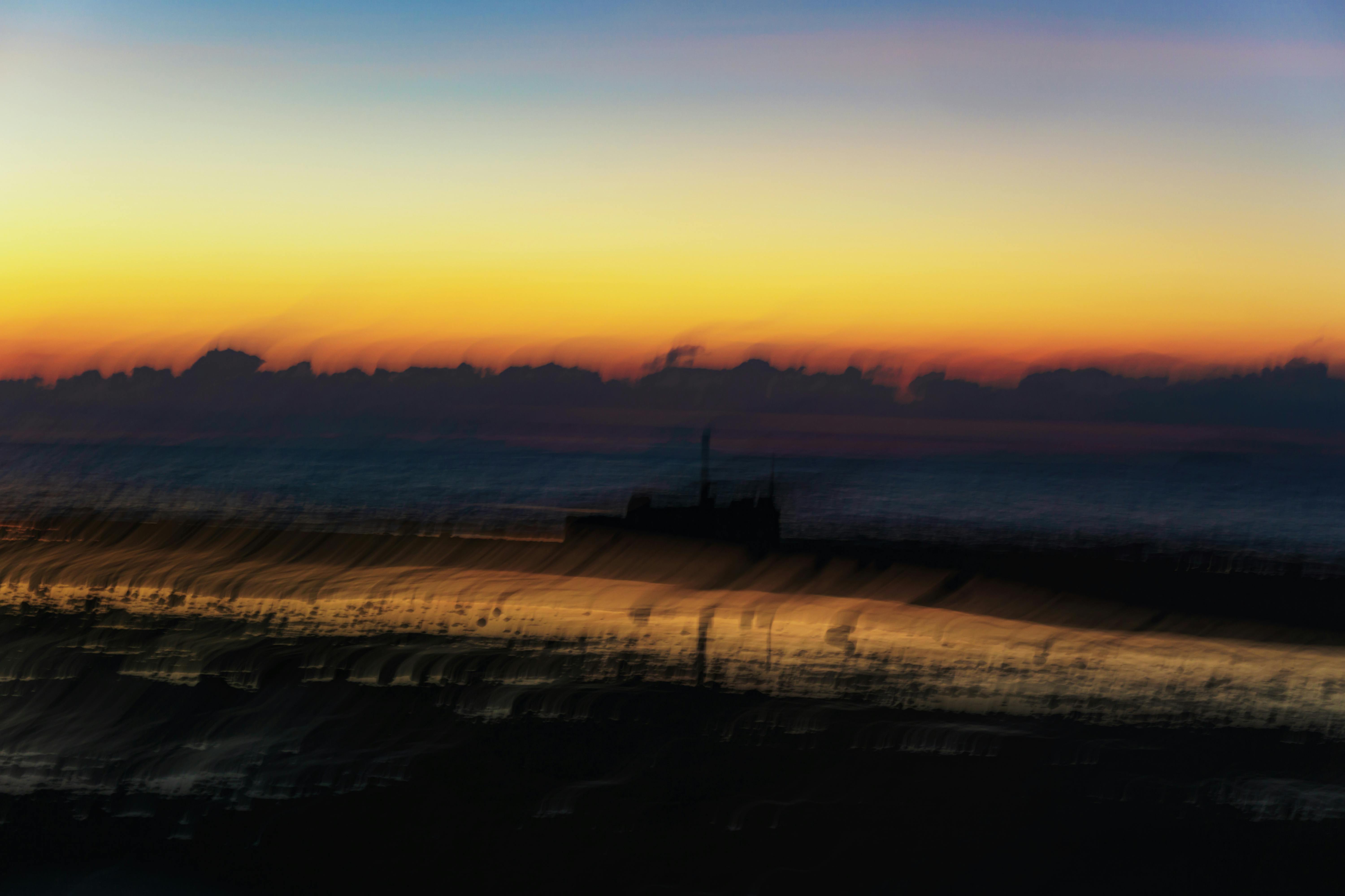 Gratis Un'immagine astratta e vibrante che cattura un tramonto sull'oceano con effetto mosso. Foto a disposizione