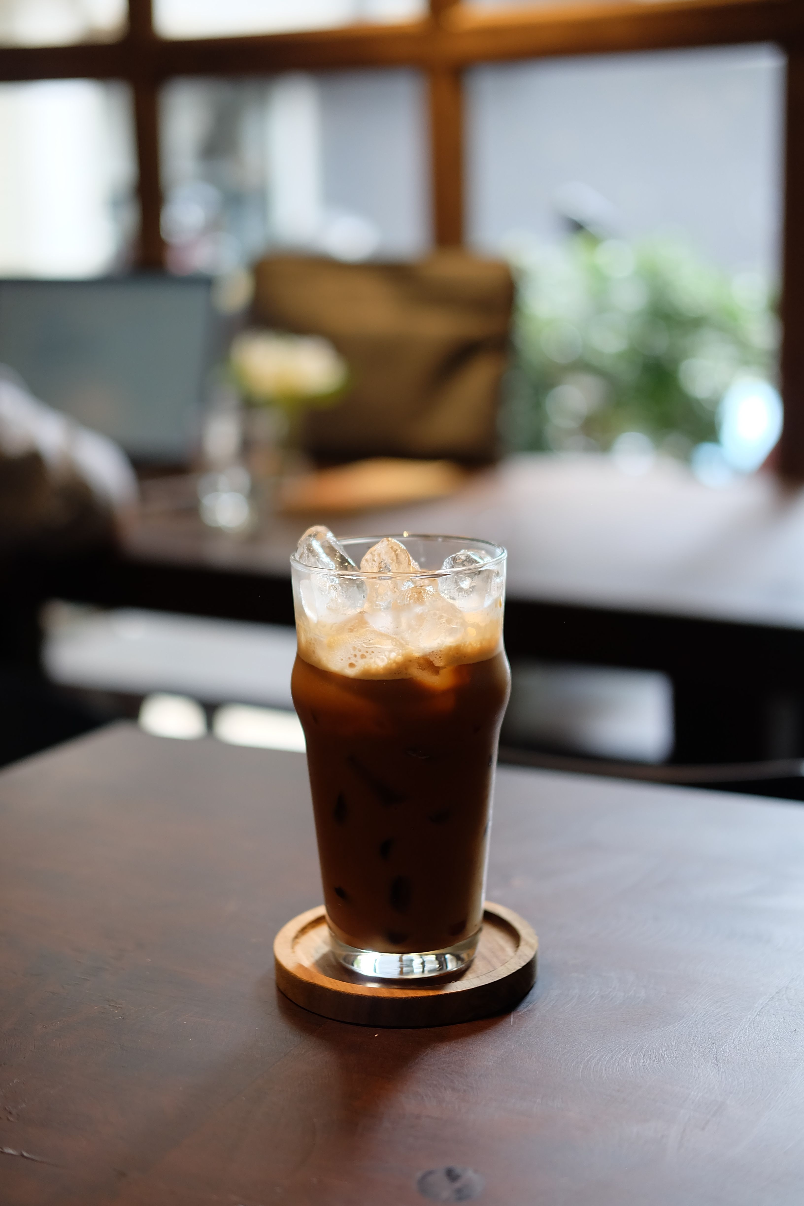 A refreshing glass of iced coffee served in a cozy indoor cafe environment.