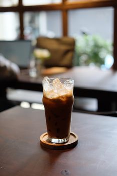 A refreshing glass of iced coffee served in a cozy indoor cafe environment.