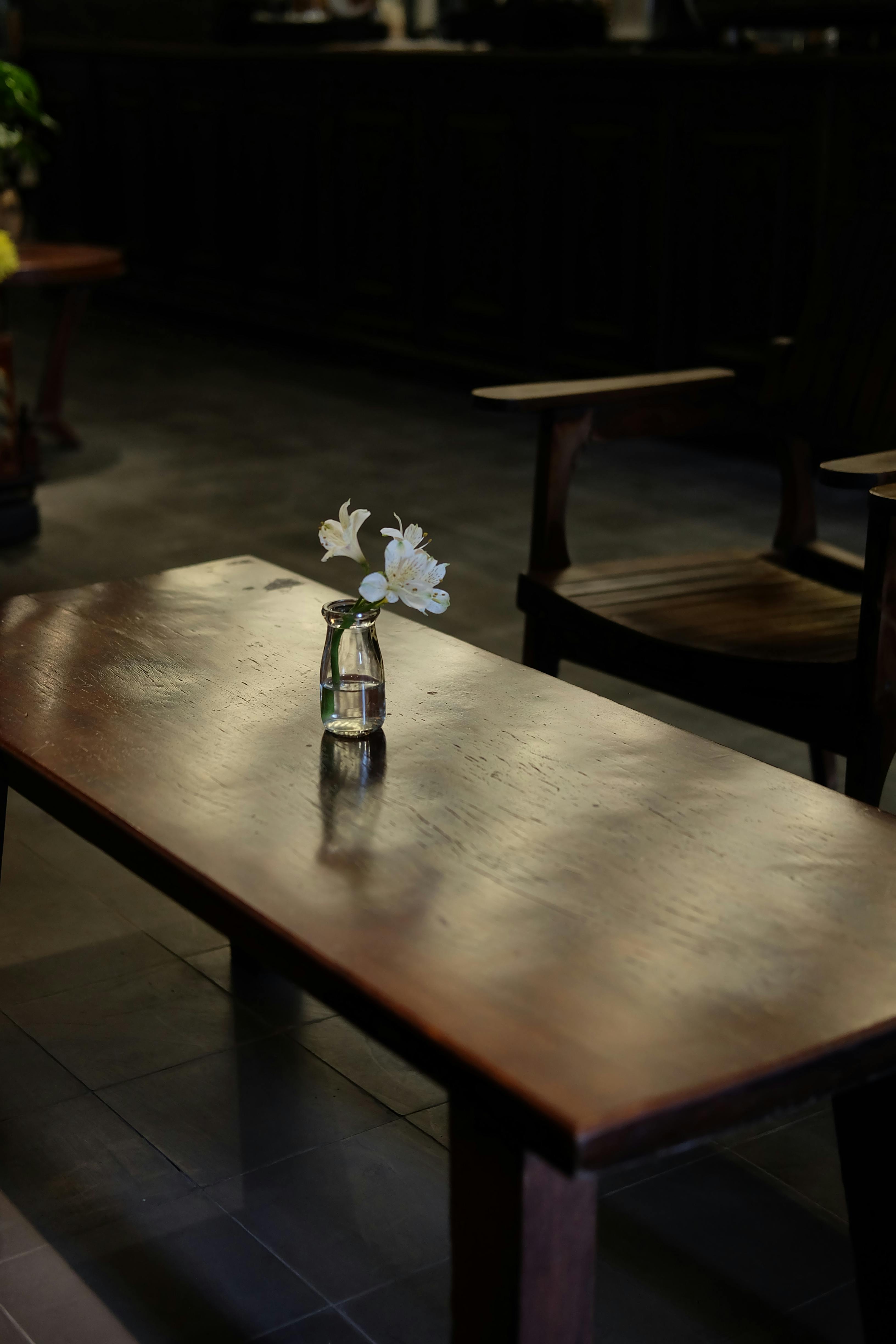 Gratis Ambiente sofisticato e minimalista con un vaso di fiori su un tavolo di legno, caratterizzato da un'illuminazione calda. Foto a disposizione