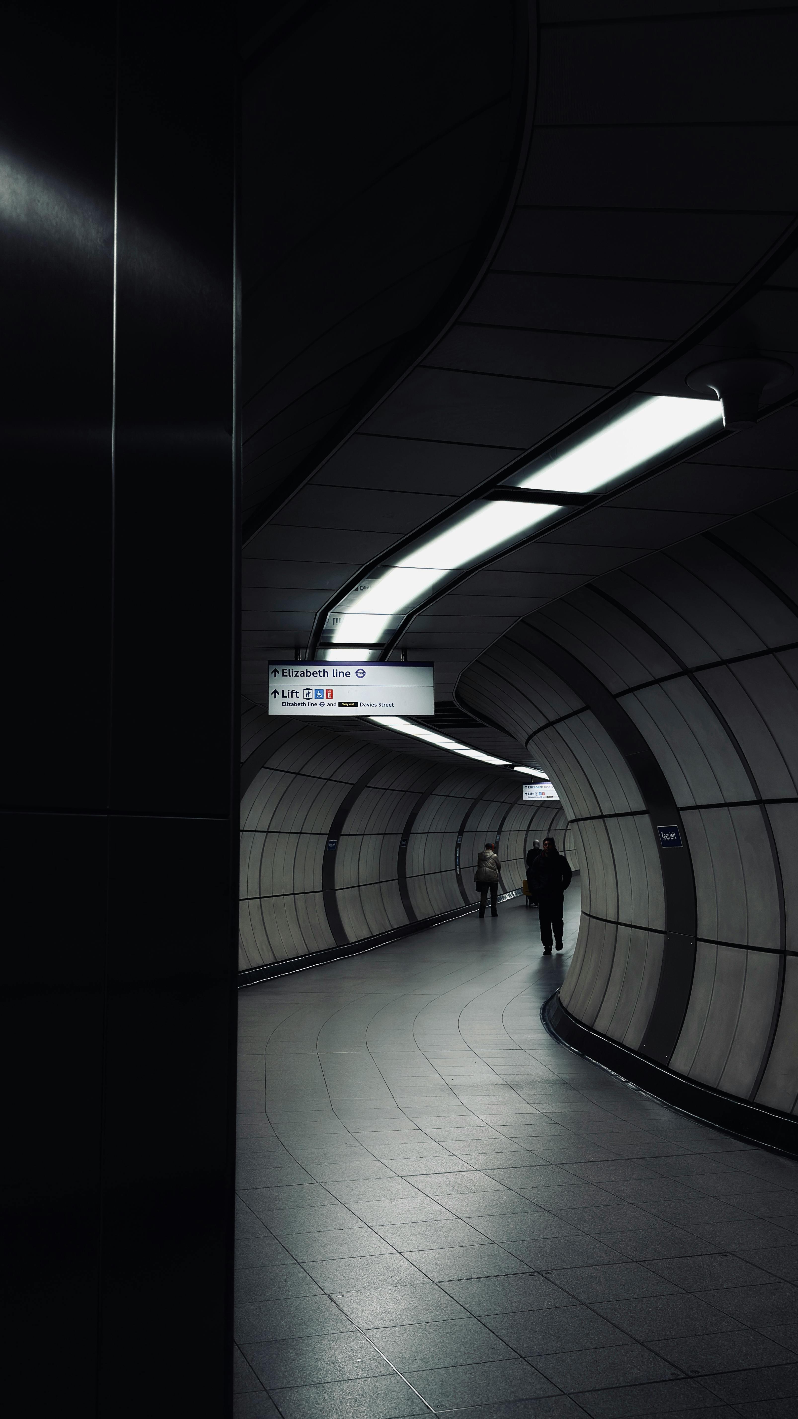 Gratis Buet t-banetunnel i Londons undergrunn, med minimal belysning og et moderne arkitektonisk design. Arkivbilde