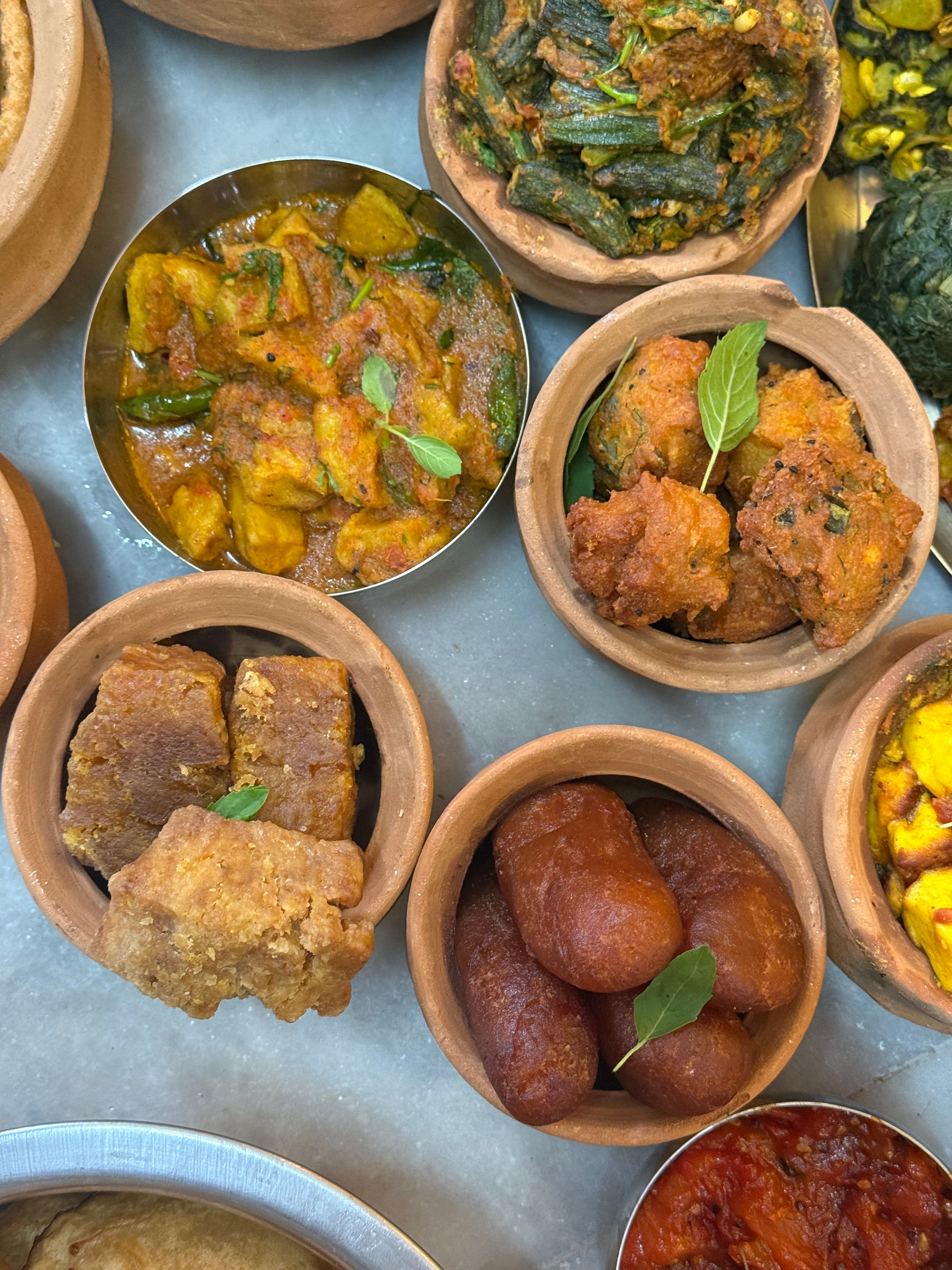 A vibrant top view of a traditional Indian thali with various curries, sweets, and snacks.