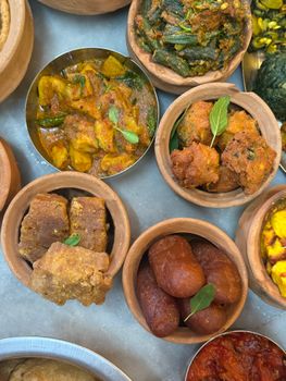 A vibrant top view of a traditional Indian thali with various curries, sweets, and snacks.