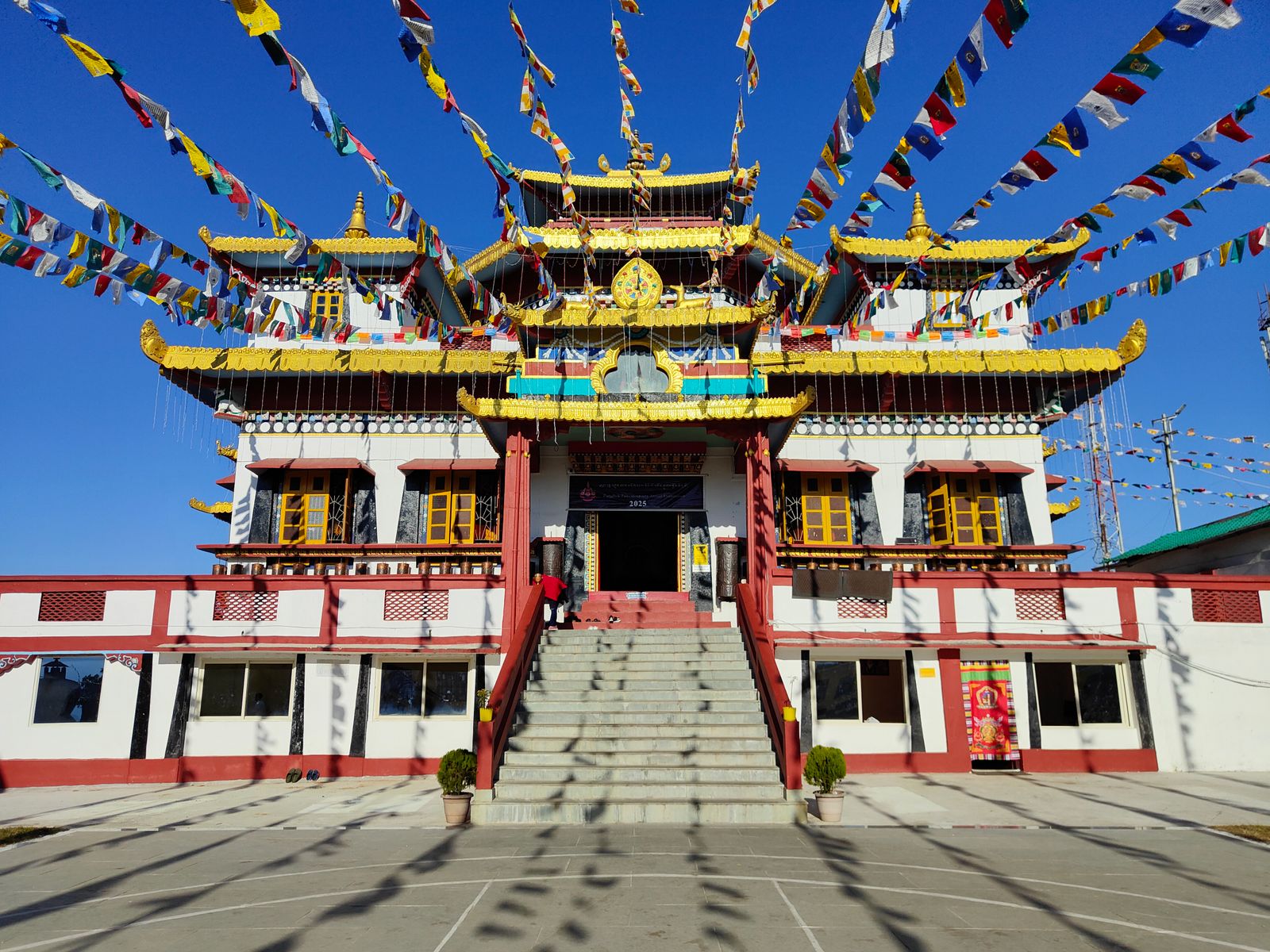 The painted facade of Ghoom Monastery at Ghum strung with prayer flags under a clear blue sky