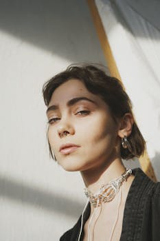 Artistic portrait of a woman with short hair and nose ring, captured in natural sunlight.