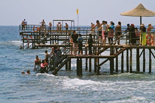 Free People enjoy a sunny day on a lively beach pier by the sea. Stock Photo