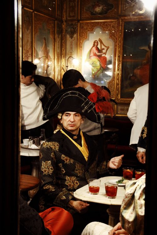Free Participants in elaborate costumes enjoy the Venice Carnival in a historic café setting. Stock Photo