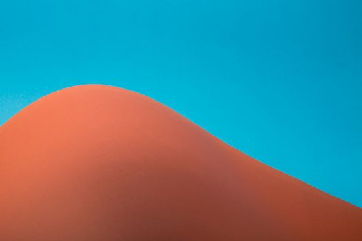 Minimalist image of a sand dune under a clear blue sky, capturing simplicity and contrast.