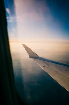 Captivating view of an airplane wing during a peaceful sunset flight, high above the clouds.
