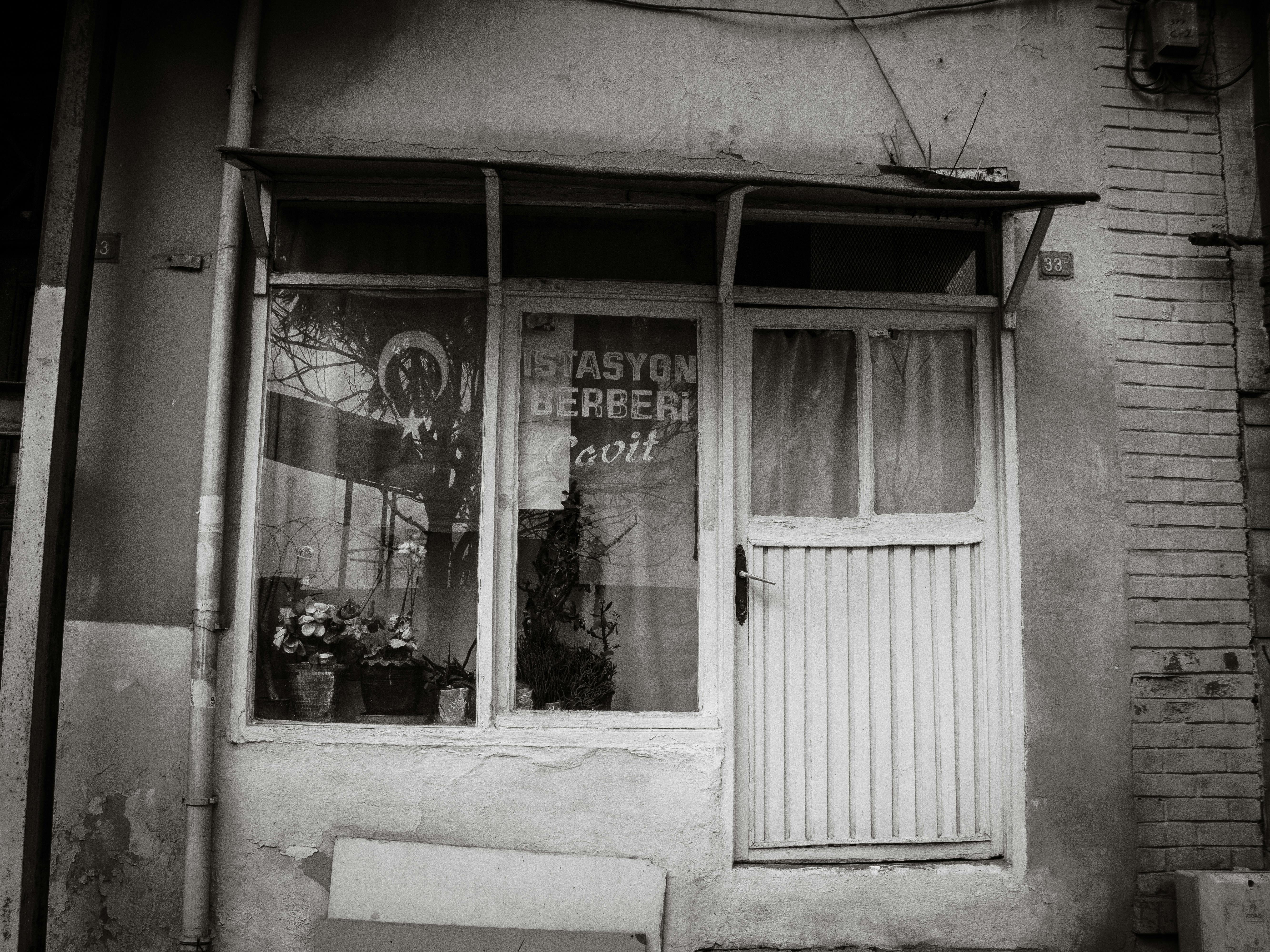 grátis Fotografia em preto e branco da entrada de uma antiga barbearia, com charme vintage e detalhes rústicos. Foto profissional