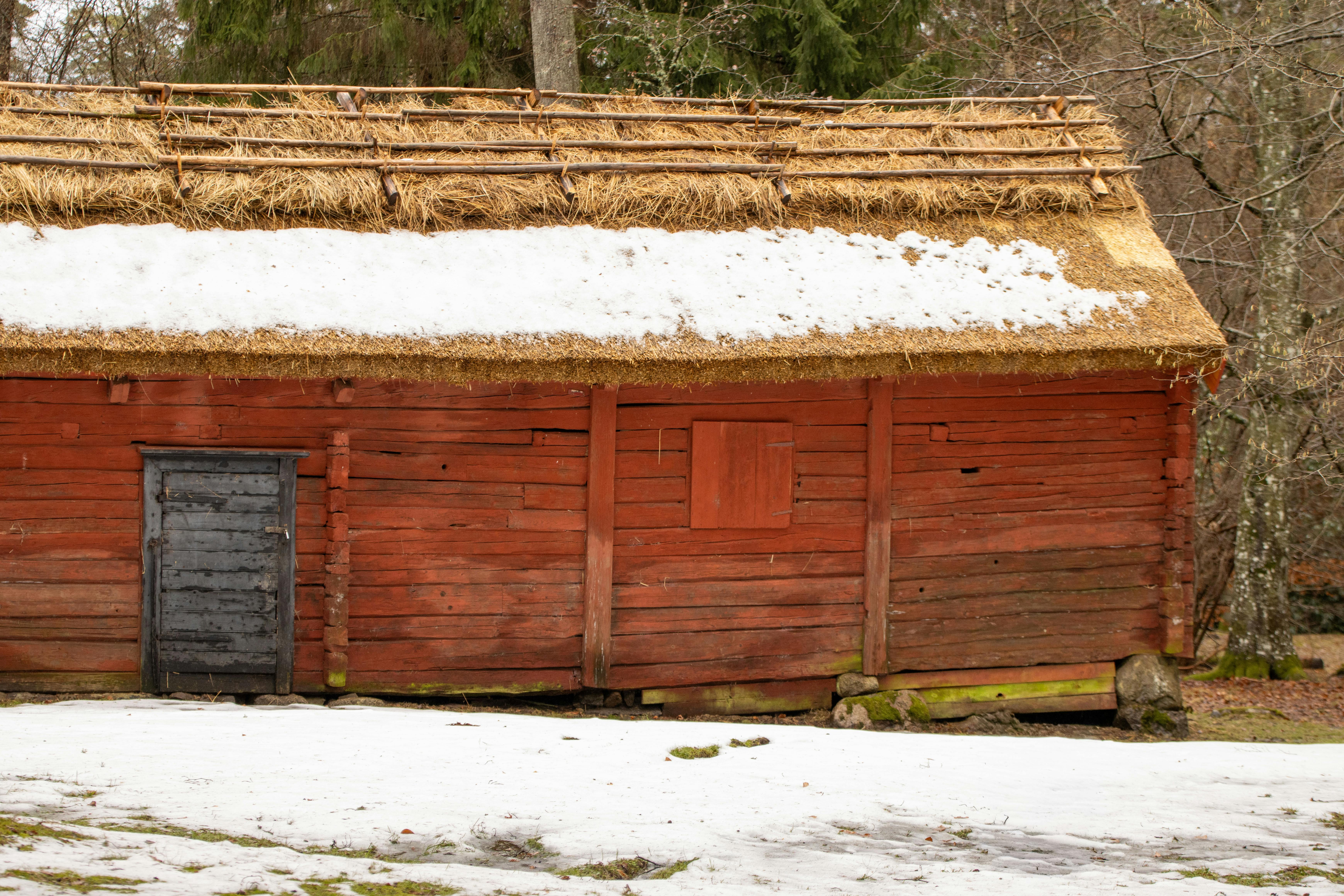 Vintage Swedish log cabin with snow-covered thatched roof in Jönköping County.