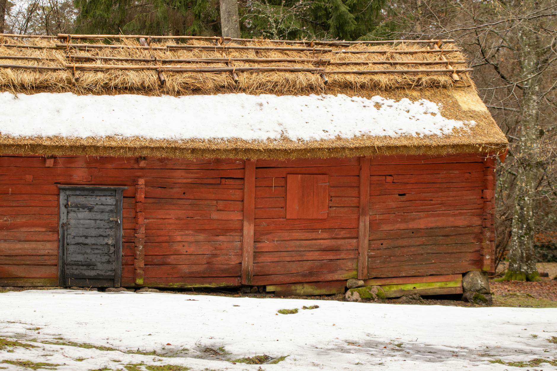 Vintage Swedish log cabin with snow-covered thatched roof in Jönköping County.