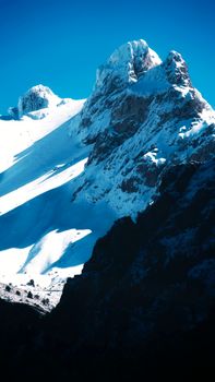 Snow-covered mountain peaks under a clear blue sky, highlighting winter's beauty.