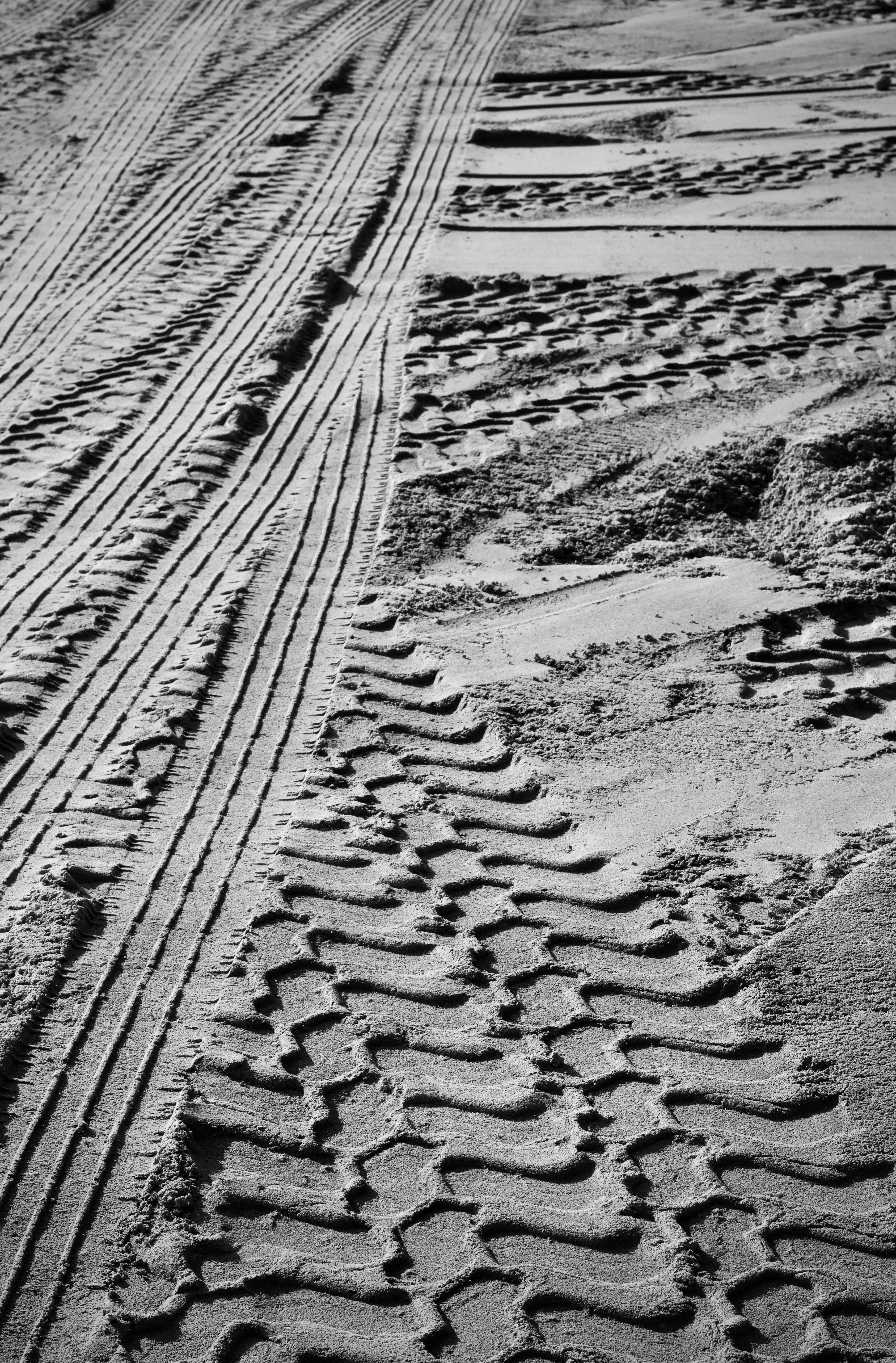 Gratuit Gros plan sur des traces de pneus complexes imprimées sur une surface de plage sablonneuse, mettant en valeur la texture et les motifs. Photos