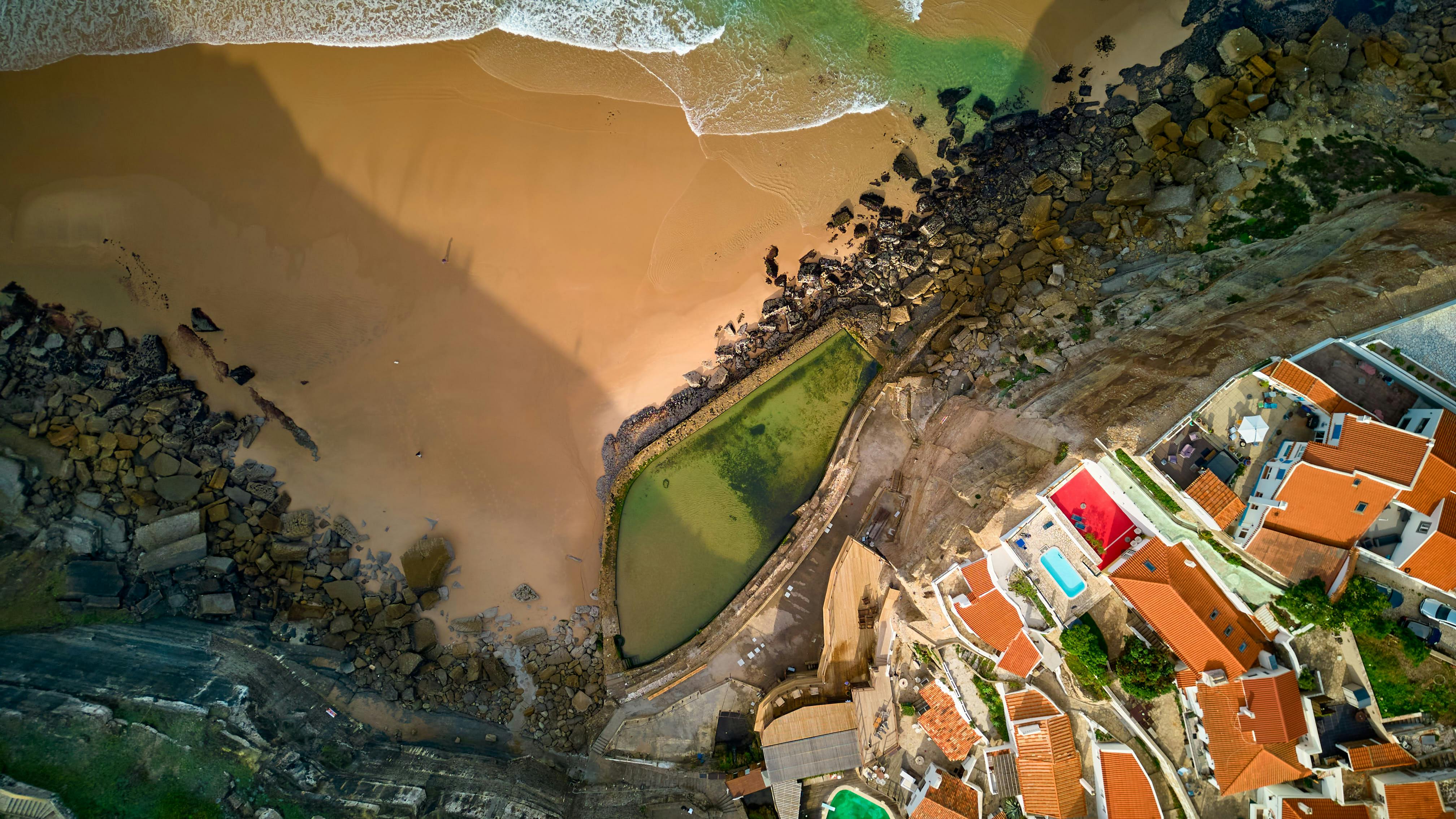Gratis Splendida ripresa aerea della spiaggia di Cascais e del villaggio costiero con i suoi vivaci tetti e la costa rocciosa. Foto a disposizione