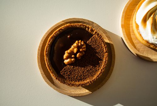 Free Cozy chocolate tart topped with walnut on wooden plate, captured in warm light. Stock Photo