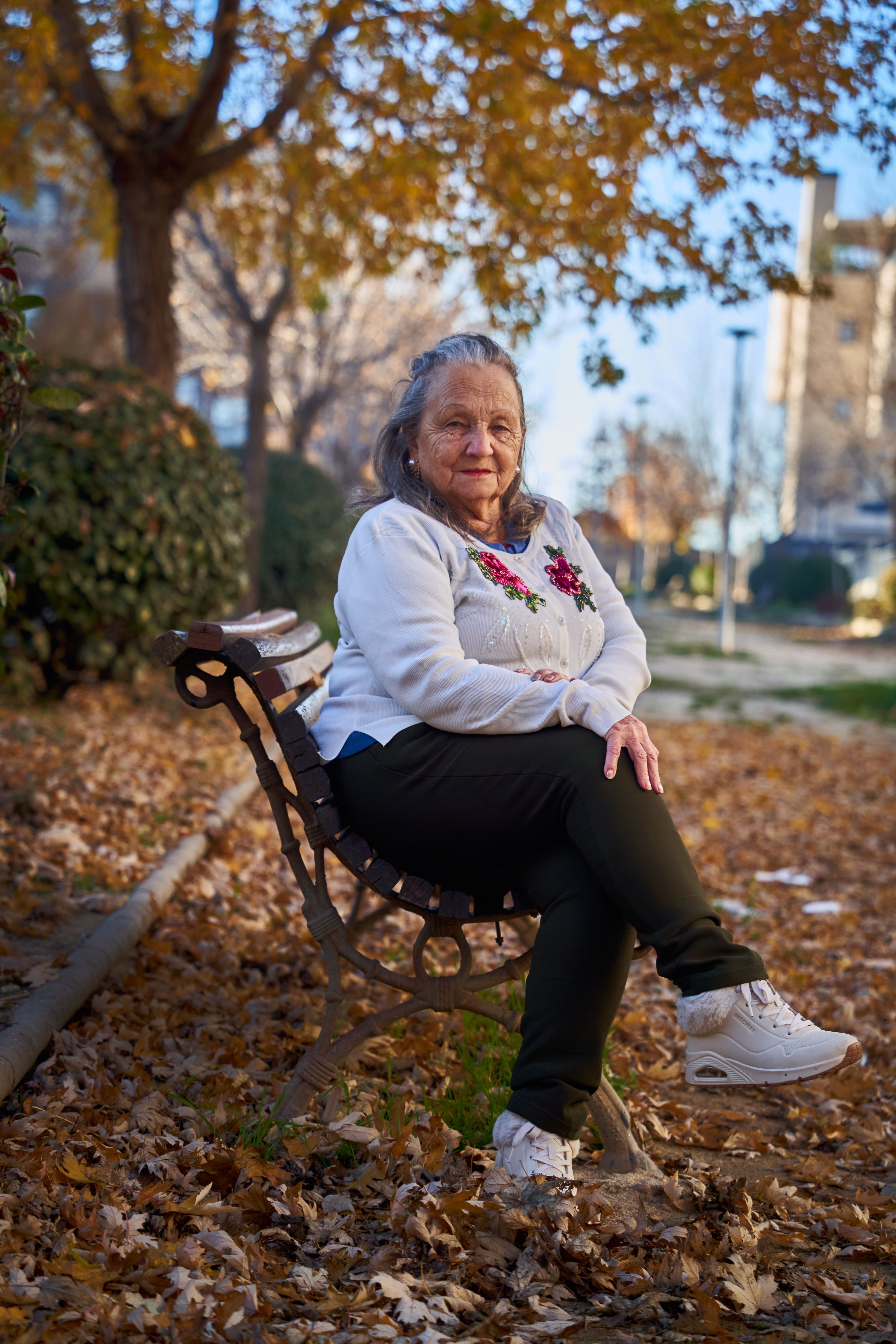 Fotomural Una mujer mayor se sienta en un banco del parque entre las hojas de otoño en Madrid, España.
