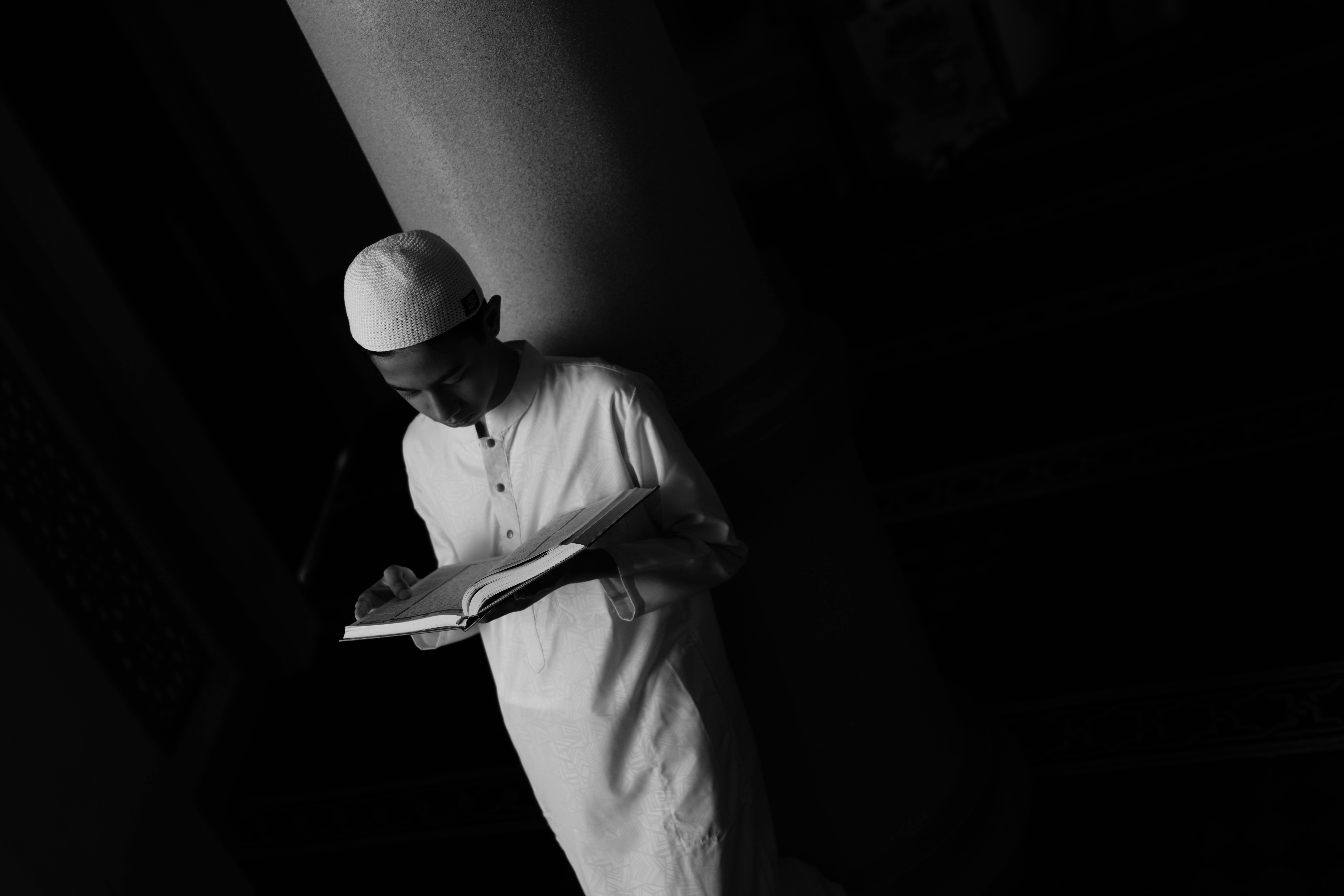 gratis Zwart-witfoto van een jonge man die een boek leest in een Indonesische moskee. Stockfoto