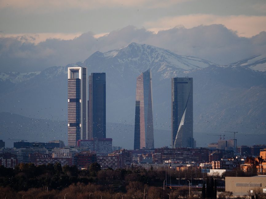 Vista del horizonte de Madrid con las Cuatro Torres contra un fondo de montañas.