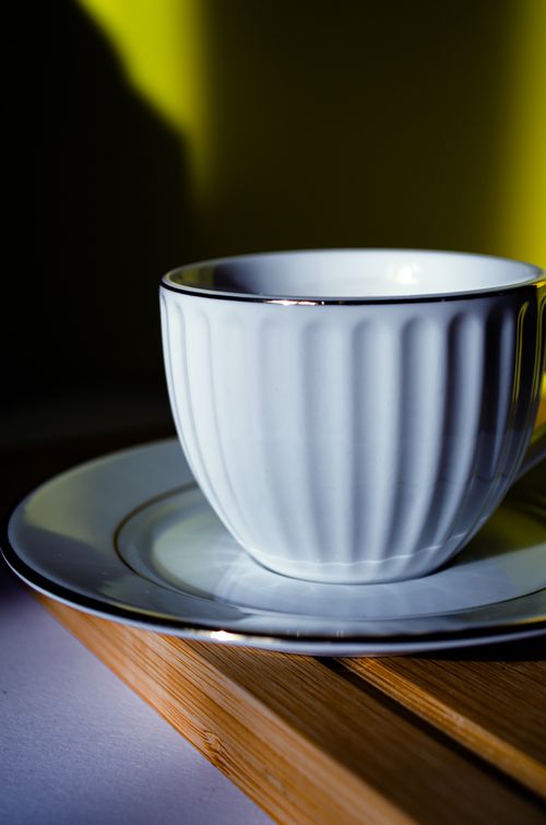 Free Elegant white ceramic cup with saucer on a bamboo tray, bathed in soft light. Stock Photo