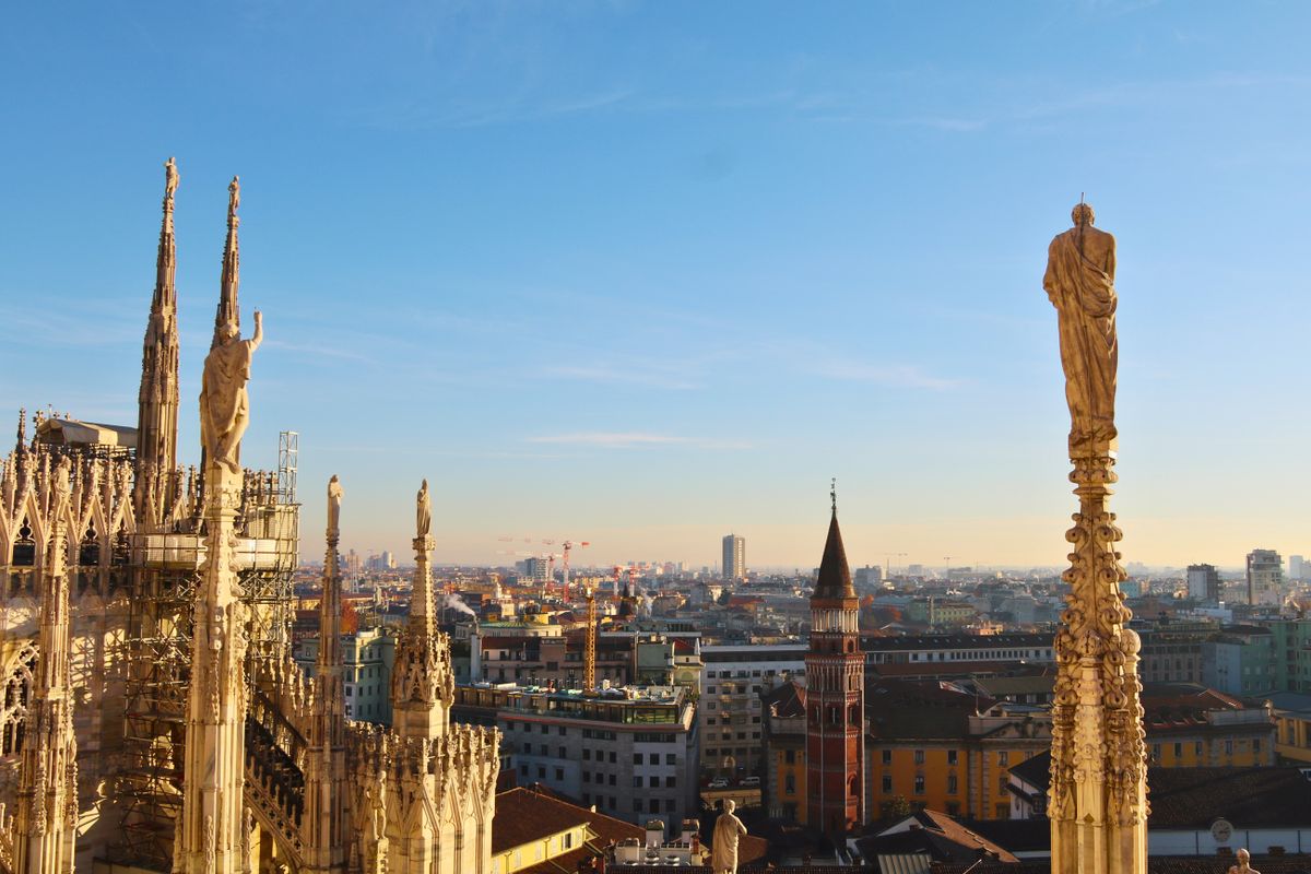 Milan's cityscape seen from the Gothic marble spires of the Duomo rooftop