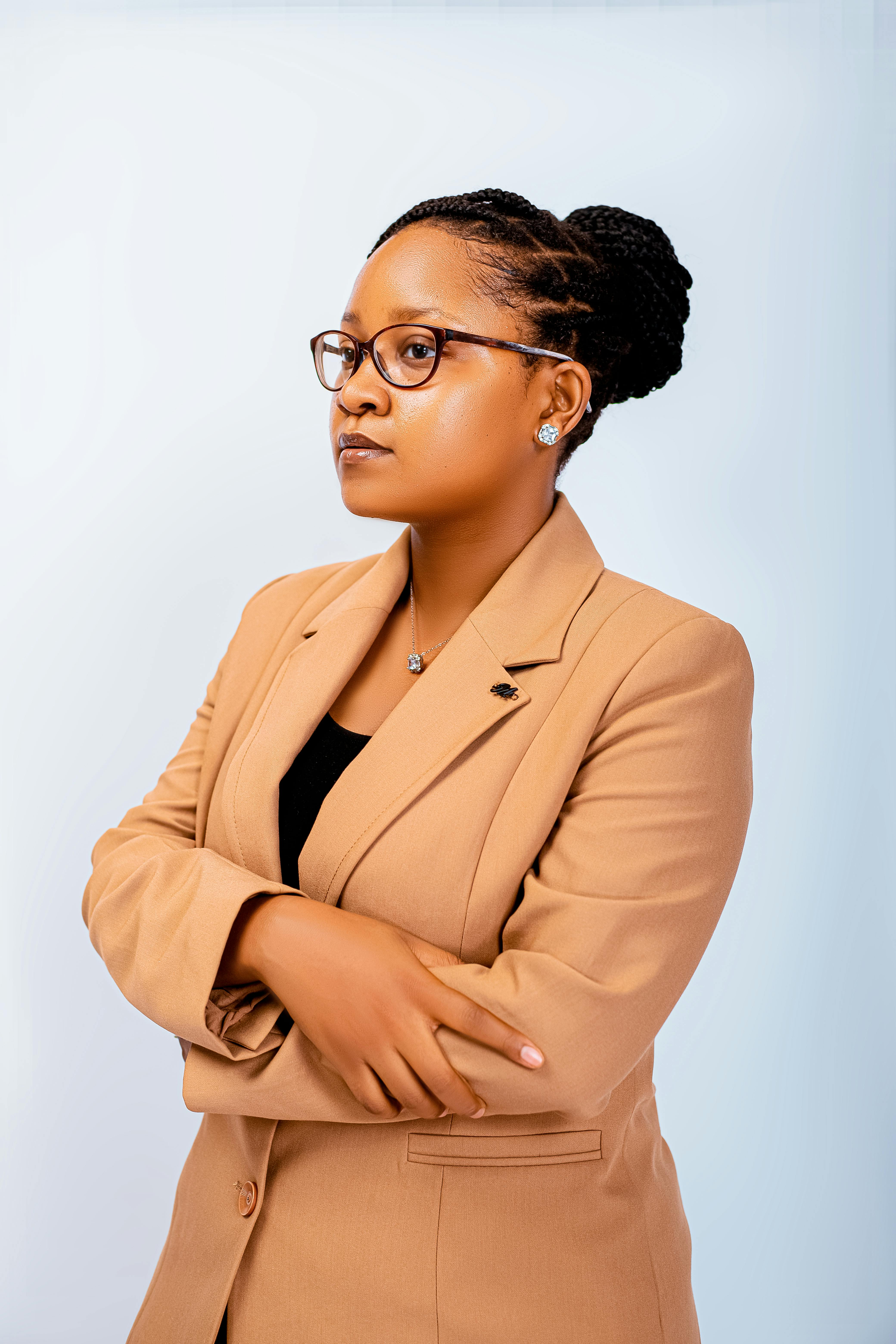 Confident businesswoman in glasses and tan blazer against a white background.