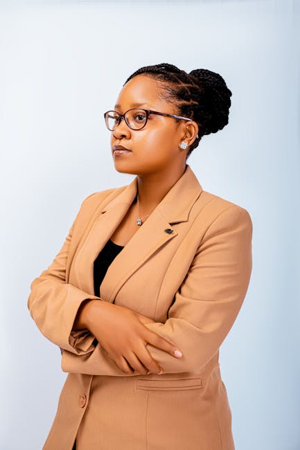 Confident businesswoman in glasses and tan blazer against a white background.