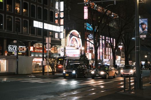 Bustling nightlife in Sapporo, Japan with vibrant neon signs and busy streets.