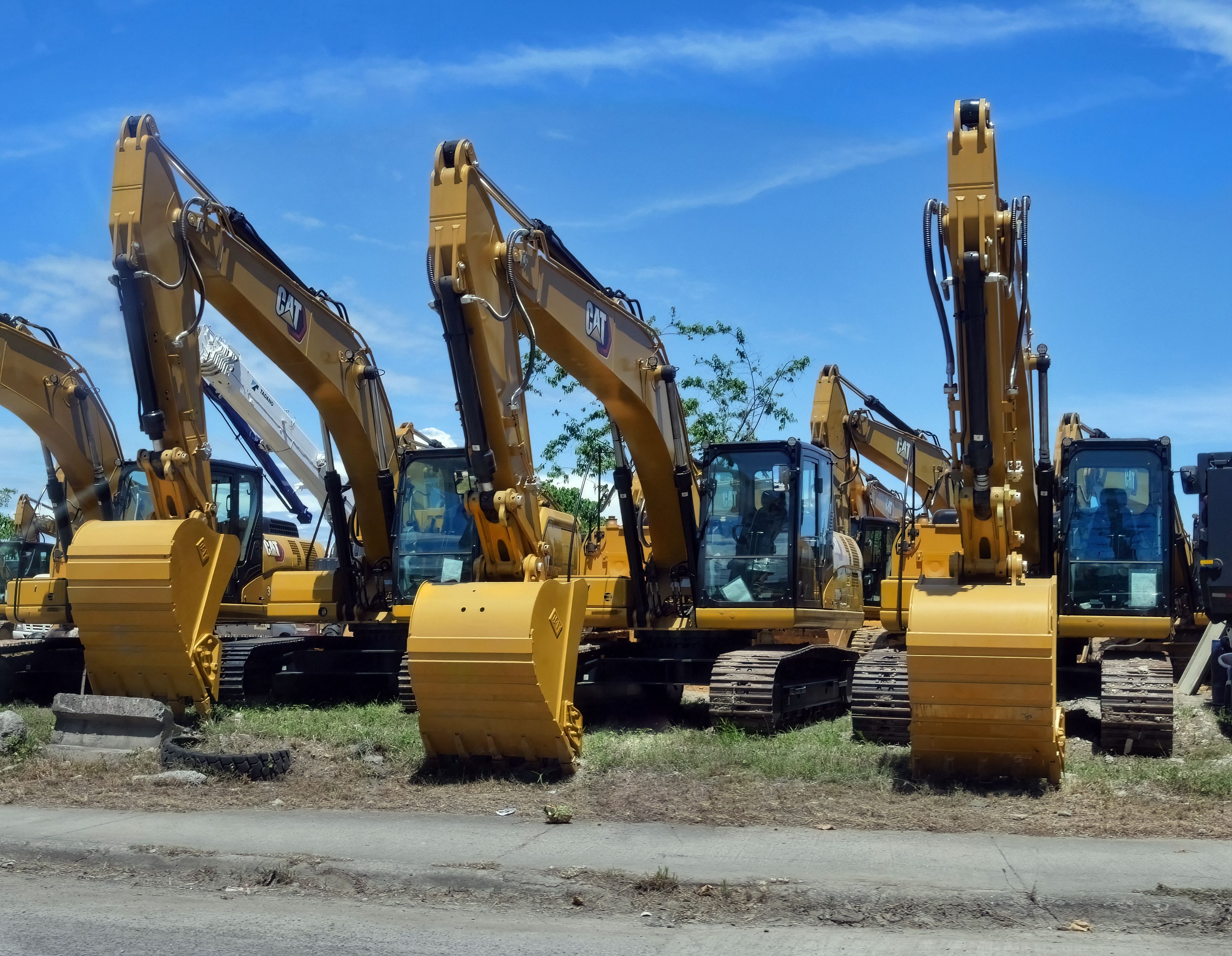 Gratuit Plusieurs excavatrices jaunes étaient alignées dans un parc à engins sous un ciel bleu dégagé. Photos