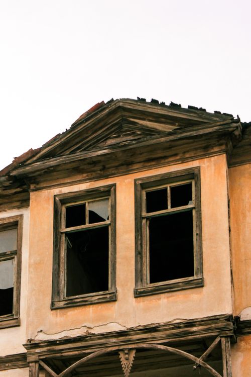 Free Aged and weathered facade of an abandoned house with broken windows and decaying wood. Stock Photo