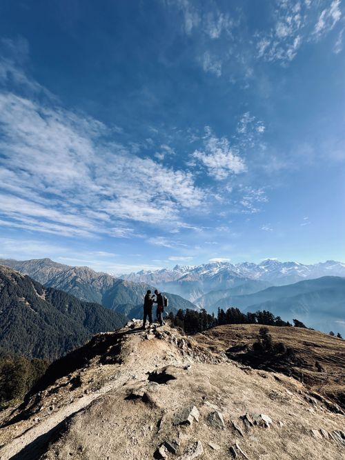 Free Breathtaking scene from a ridge with people overlooking the Himalayan range under a clear blue sky. Stock Photo