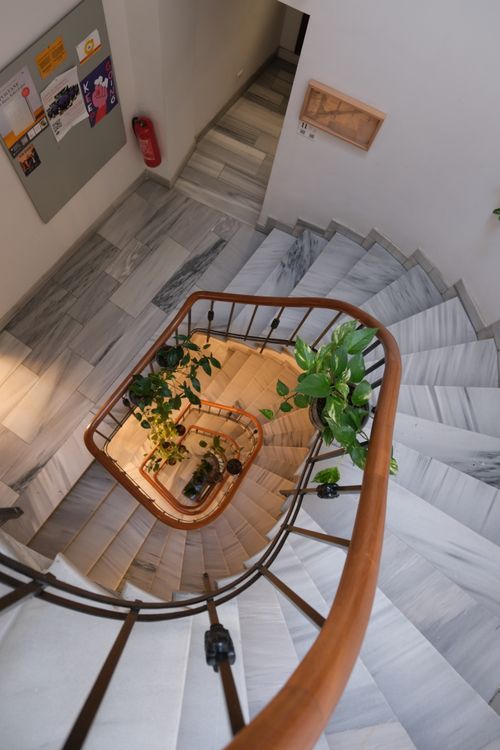 Free Top view of a marble spiral staircase adorned with plants, creating a serene indoor atmosphere. Stock Photo