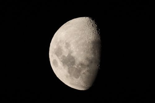 Free Detailed view of a waxing gibbous moon highlighted against a dark night sky, showcasing lunar craters. Stock Photo