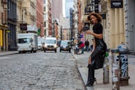 一名身穿时尚黑色服装的女子在城市的鹅卵石街道上摆着姿势